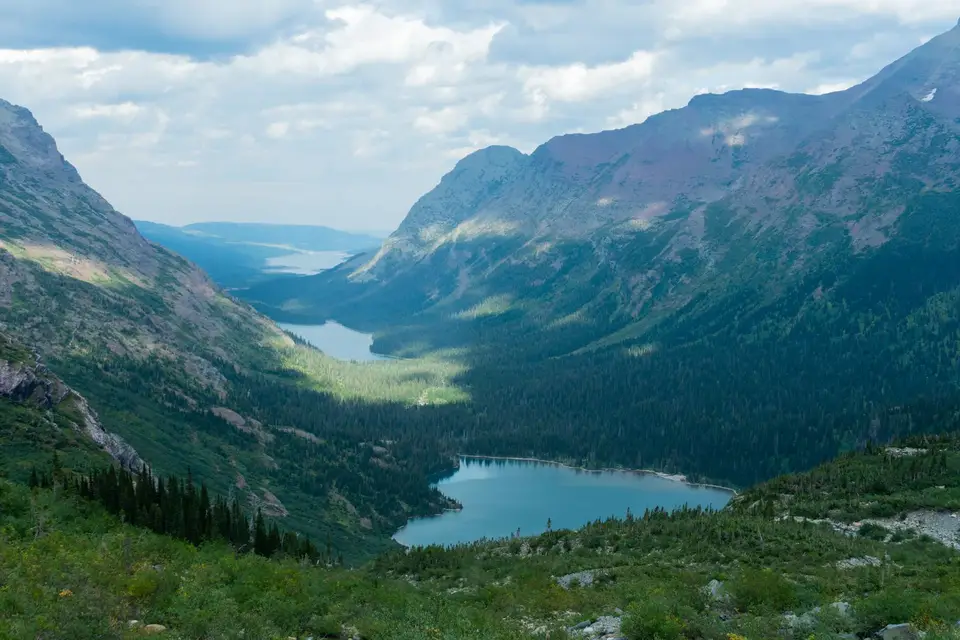 Turquoise Grinnell Lake far below in a green valley, seen from the Grinnell Glacier trail