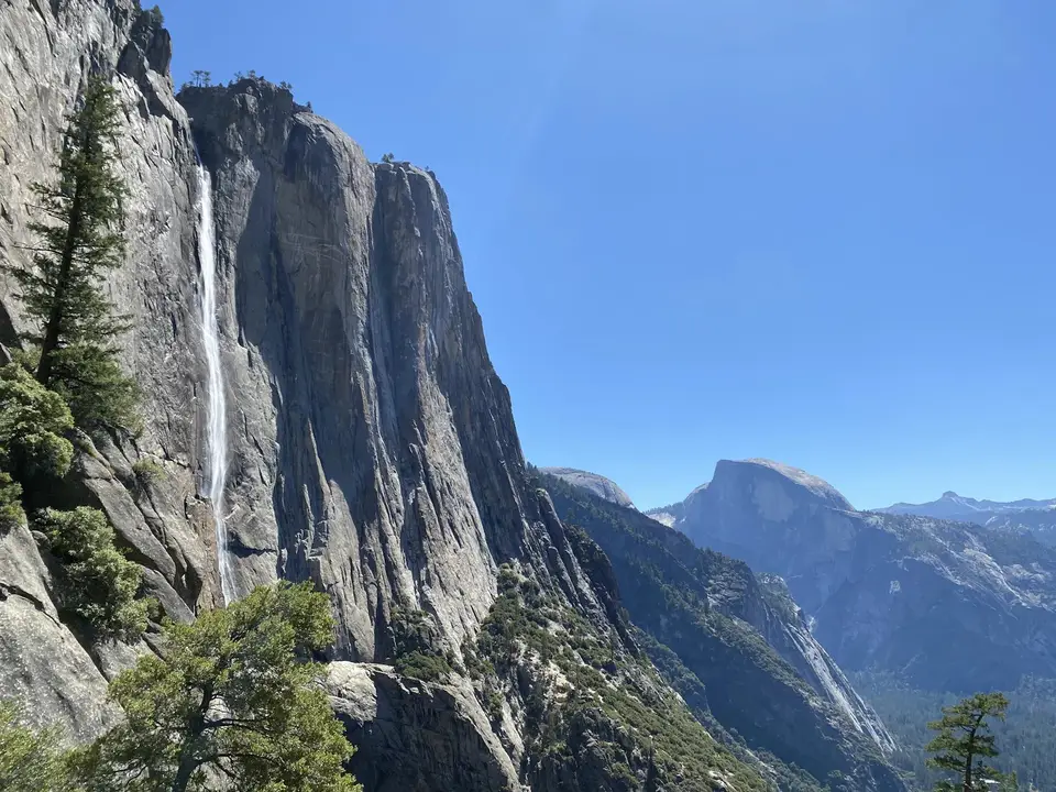 Yosemite Falls pouring down a granite cliff with Half Dome in the distance